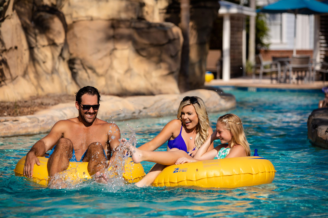 Reunion Resort water park: Family playfully splashing each other on lazy river ride.