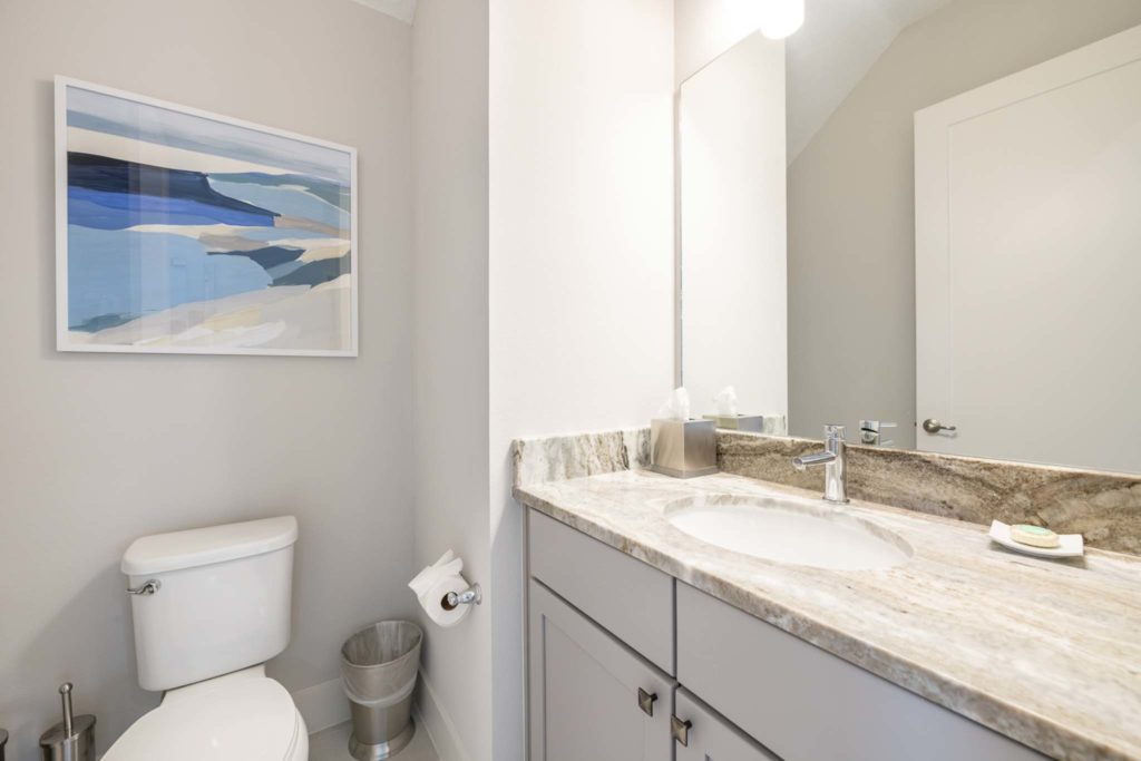 Half bath with sink, mirror, and toilet in an elegant 8-bedroom Bear’s Den Resort Orlando residence.