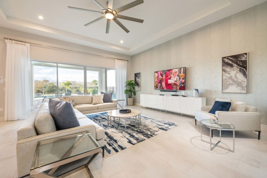 Spacious living room with couch, coffee table, TV, and sliding door access to outdoor private pool in an elegant 8-bedroom Bear’s Den Resort Orlando residence.
