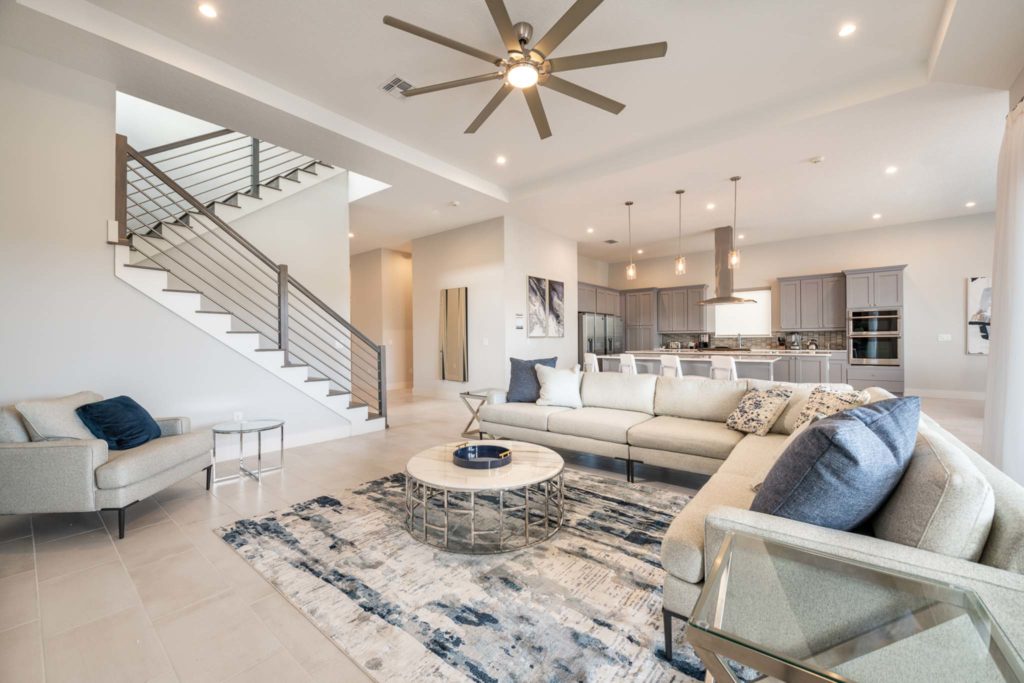 Living room, kitchen, and stairway to upper level in an elegant 8-bedroom Bear’s Den Resort Orlando residence.