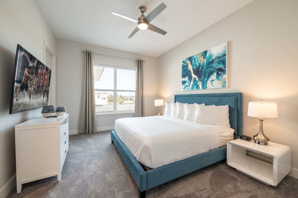 Large king bed and wall-mounted TV in an elegant 8-bedroom Bear’s Den Resort Orlando residence.