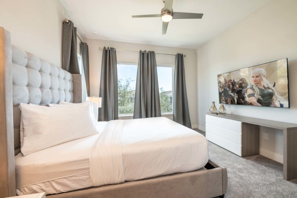 Large king bed and wall-mounted TV in an elegant 8-bedroom Bear’s Den Resort Orlando residence.