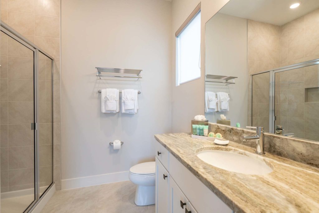 Bathroom with standing shower, toilet, sink, and mirror in an elegant 8-bedroom Bear’s Den Resort Orlando residence.