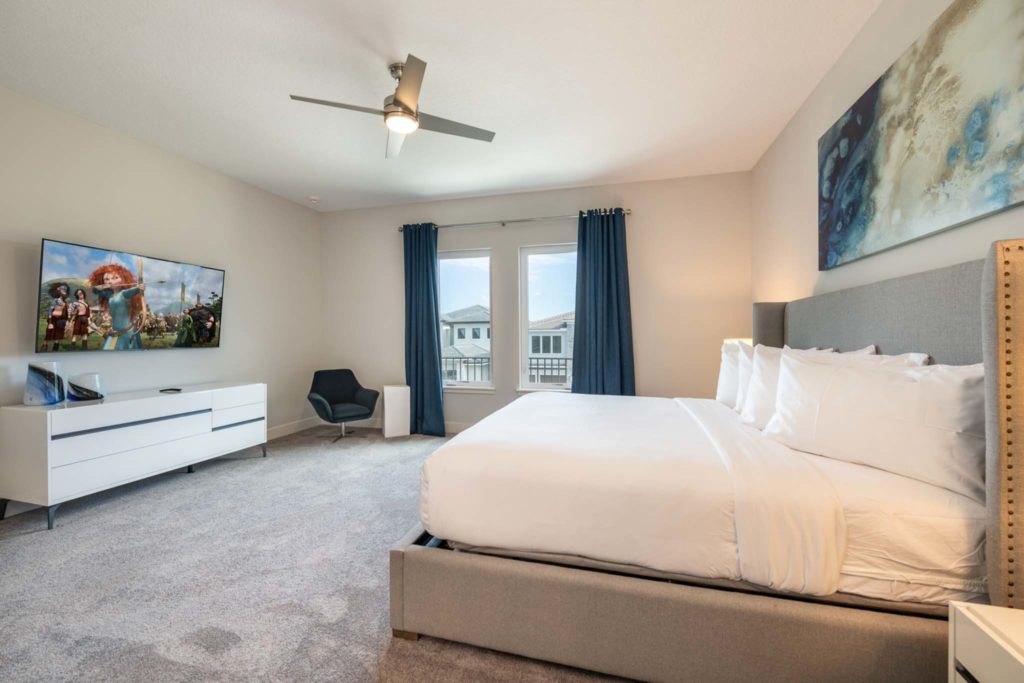 Spacious bedroom with large king bed and wall-mounted TV in an elegant 8-bedroom Bear’s Den Resort Orlando residence.