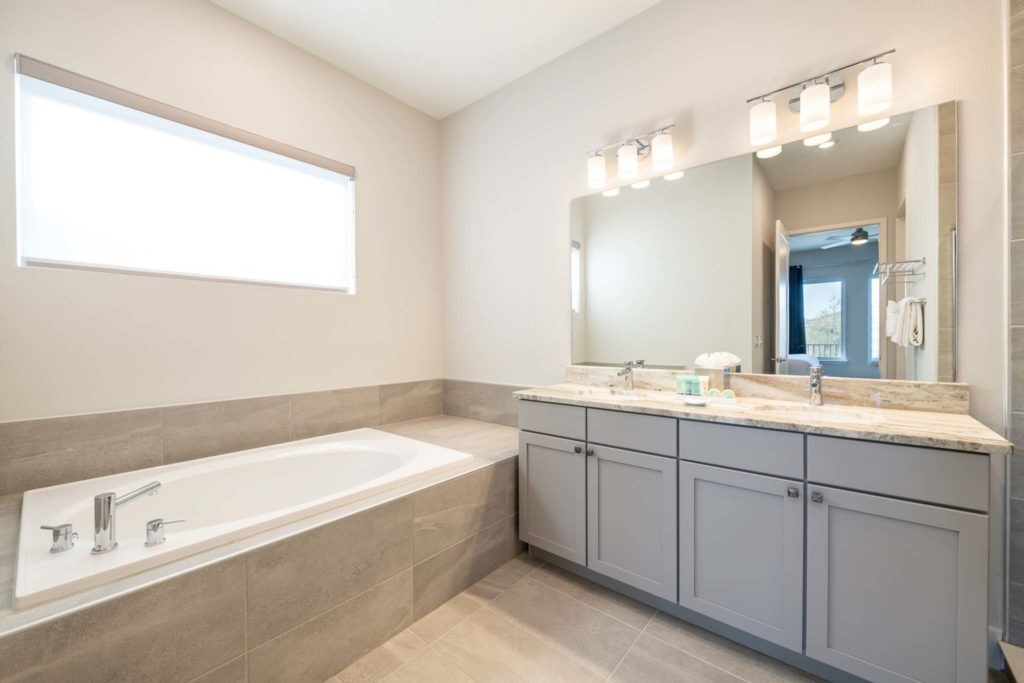 Large bathtub, sink, and mirror in an elegant 8-bedroom Bear’s Den Resort Orlando residence.