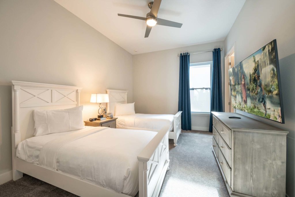 Double twin beds and large, wall-mounted TV in an elegant 8-bedroom Bear’s Den Resort Orlando residence.