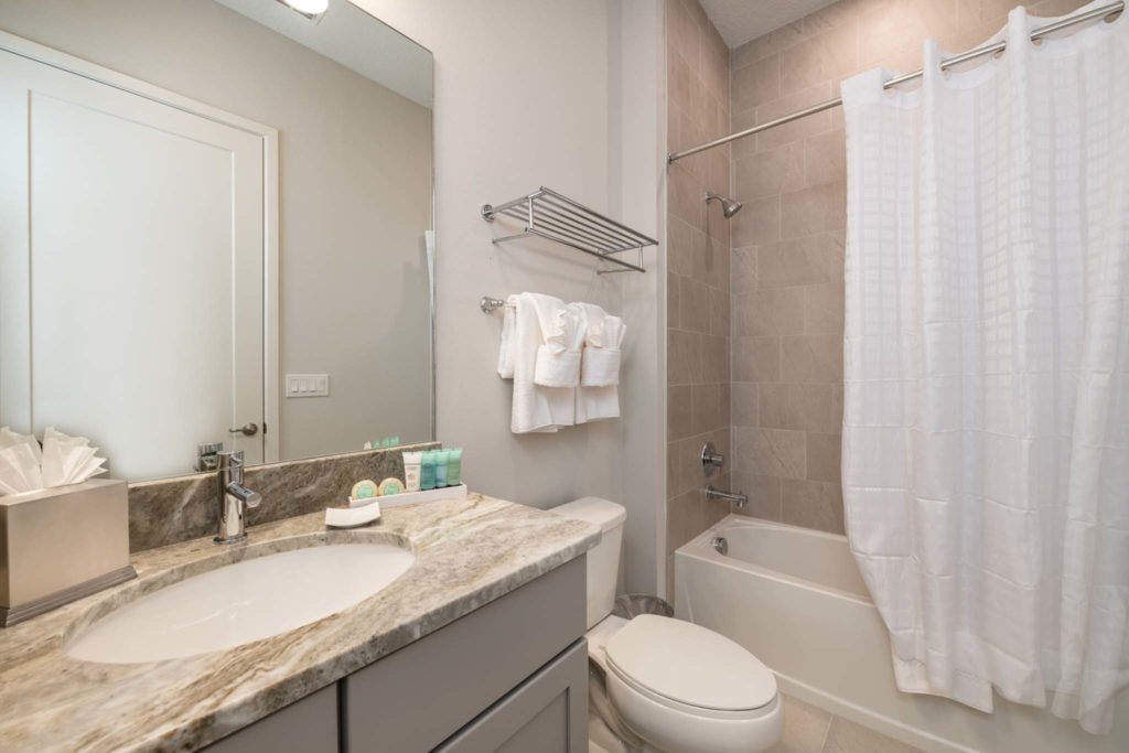 Bathtub, toilet, sink, and mirror in an elegant 8-bedroom Bear’s Den Resort Orlando residence.