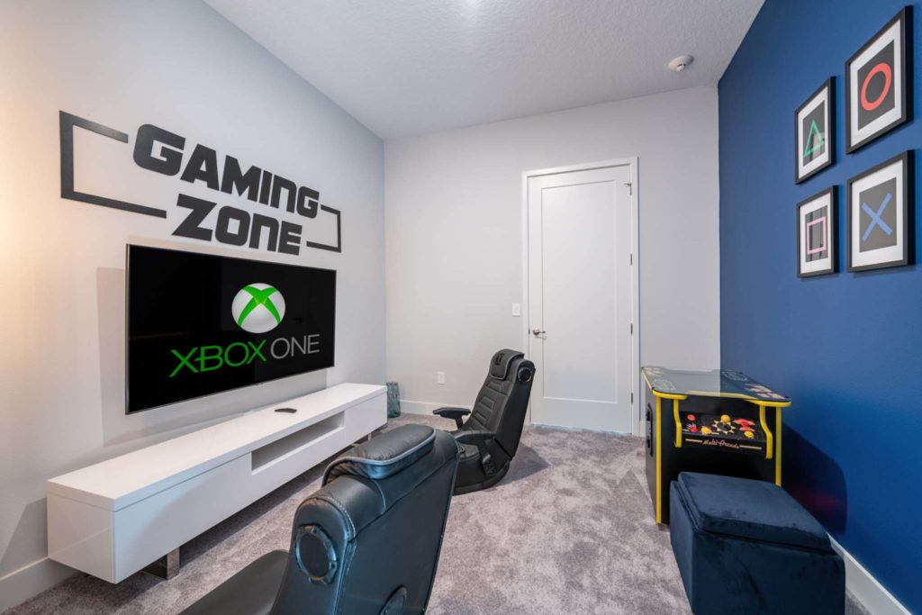 Large game room with specialty gaming chairs, Xbox One console, and cocktail-style arcade table in an elegant 8-bedroom Bear’s Den Resort Orlando residence.
