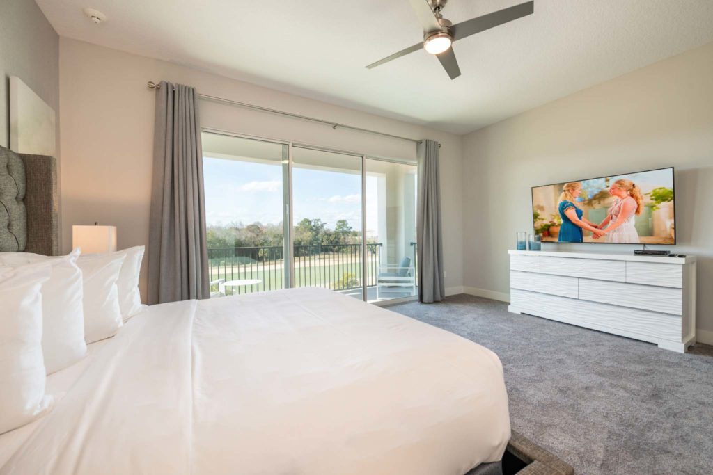 Spacious master bedroom with large king bed and balcony access in an elegant 8-bedroom Bear’s Den Resort Orlando residence.