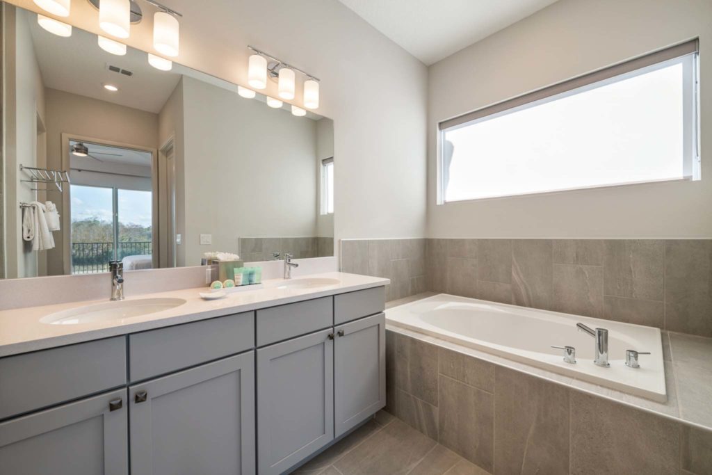 Large bathtub and double sink with mirror in an elegant 8-bedroom Bear’s Den Resort Orlando residence.