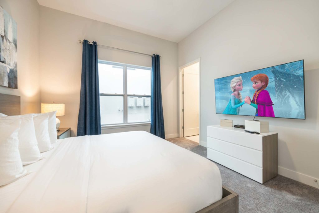 Large king bed and wall-mounted TV in an elegant 8-bedroom Bear’s Den Resort Orlando residence.