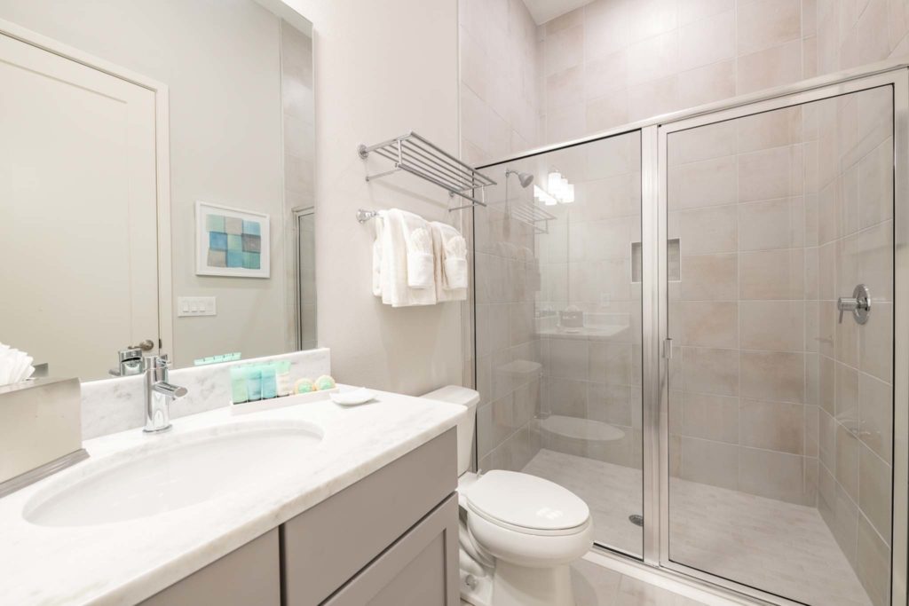 Bathroom with standing shower, toilet, sink, and mirror in an elegant 8-bedroom Bear’s Den Resort Orlando residence.