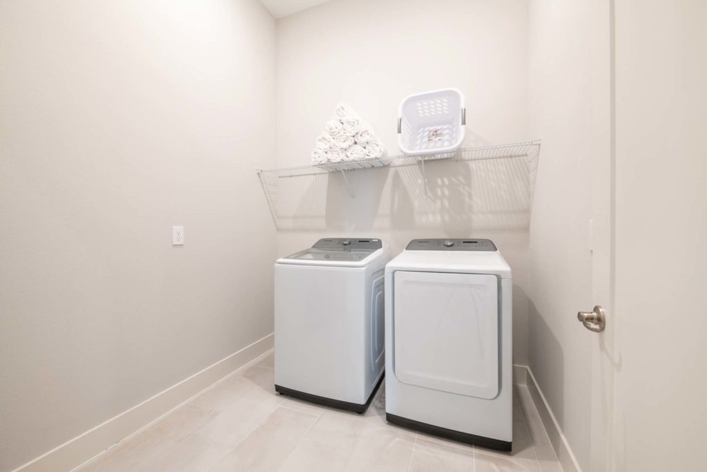 Laundry room with washer and drier in an elegant 8-bedroom Bear’s Den Resort Orlando residence.