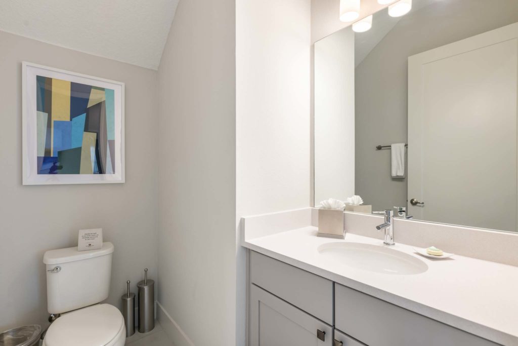Half bathroom with sink, toilet, and large mirror.