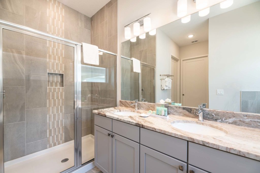 Double sink and large, wall-to-wall mirror, and standing shower stall.