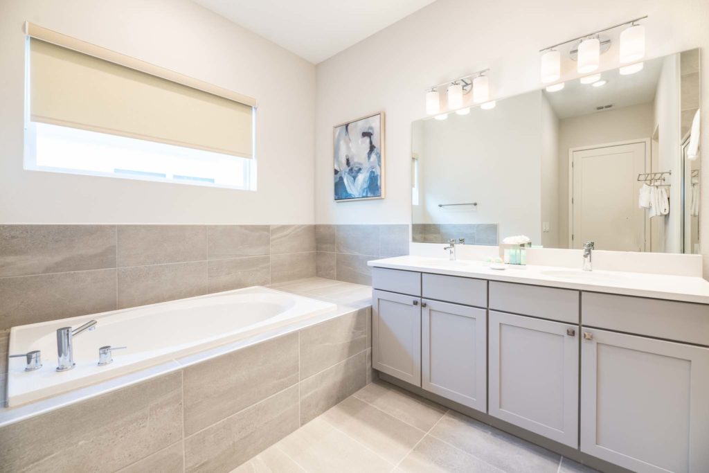 Drop-in bathtub next to a double sink with large mirror.