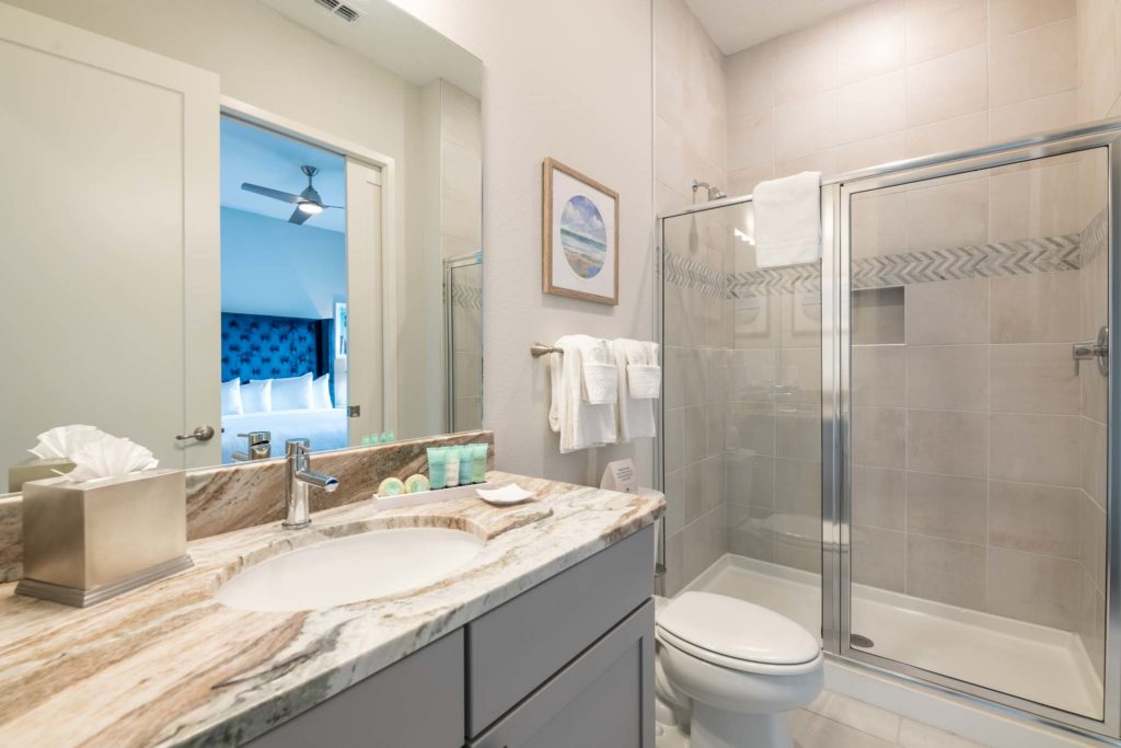 Bathroom with sink, mirror, toilet, and standing shower stall.