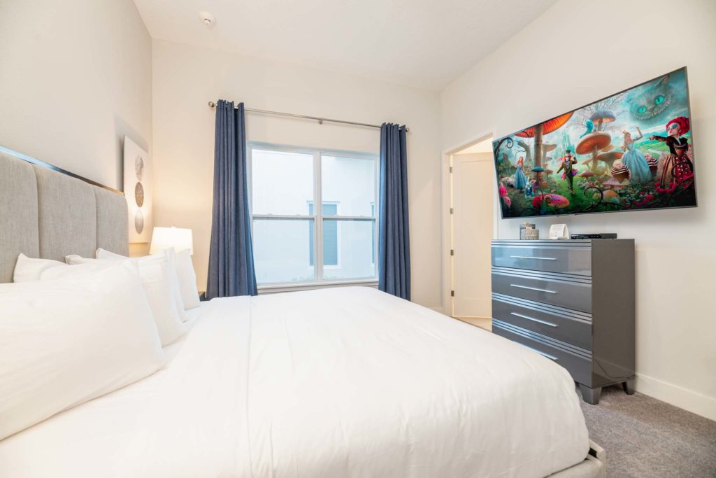 Bedroom suite with large king bed, plush headboard, and wall-mounted TV.