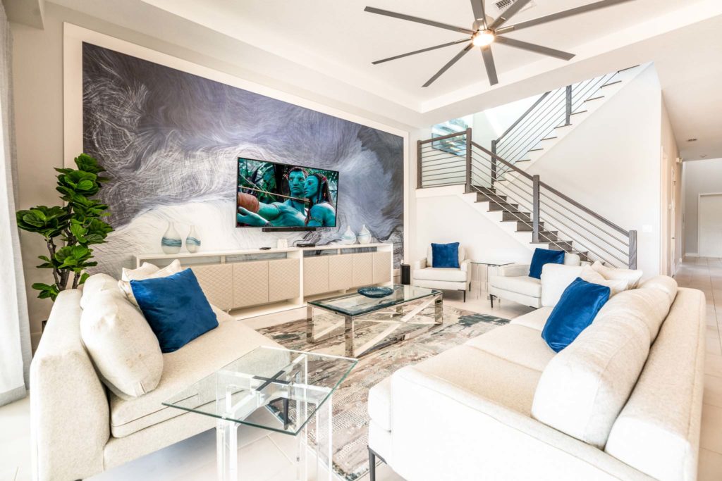 Furnished living room with large, decorative wall art mural behind a wall-mounted TV.