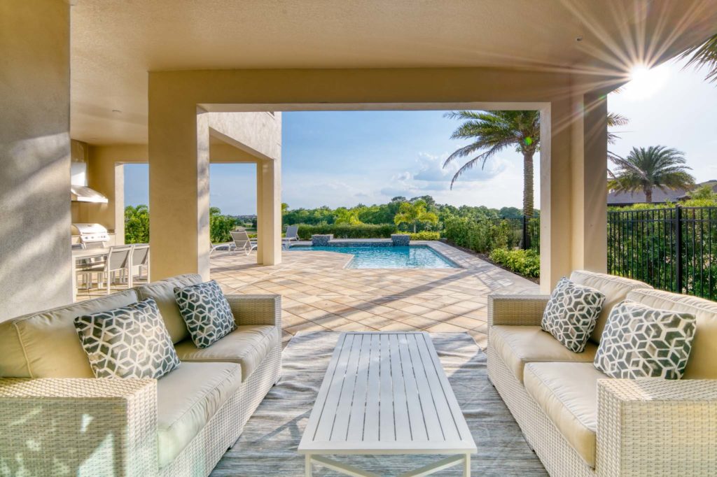 Covered outdoor lanai overlooking a private backyard pool on a sunny day.