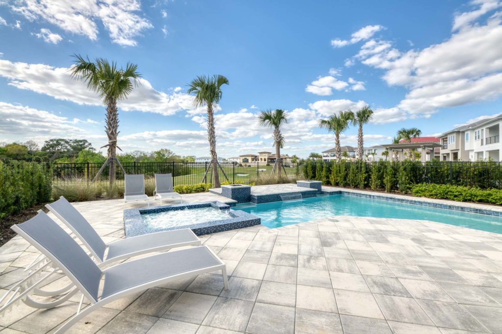 Private backyard patio with pool, spa, waterfall, and lounge chairs with golf course view.