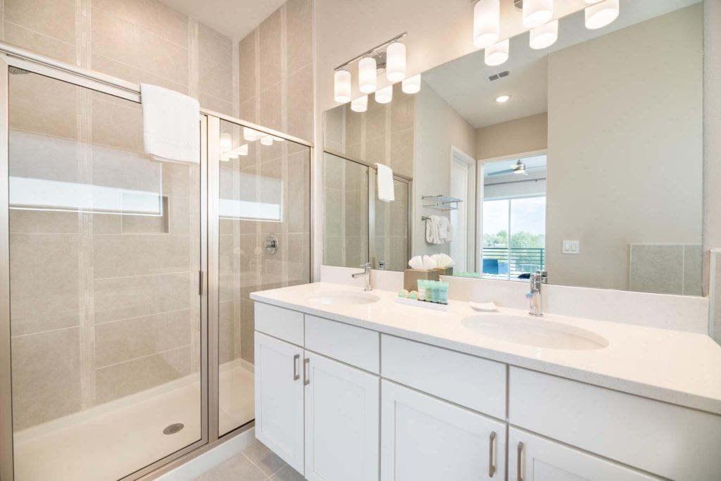 Bathroom with double sink, large mirror, and glass door shower.