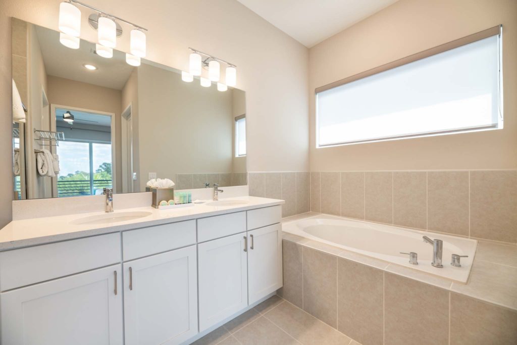 Bathroom with drop-in bathtub, double sink, and large mirror.