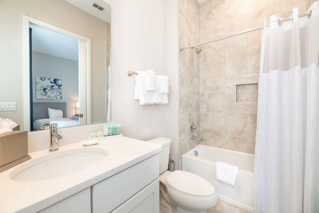 Bathroom with alcove tub, toilet, sink, and mirror.