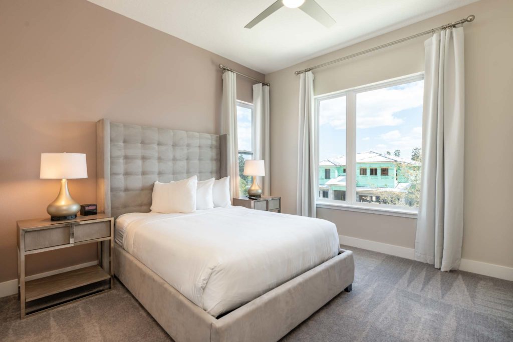 Spacious bedroom with large king bed, plush headboard, and large windows.