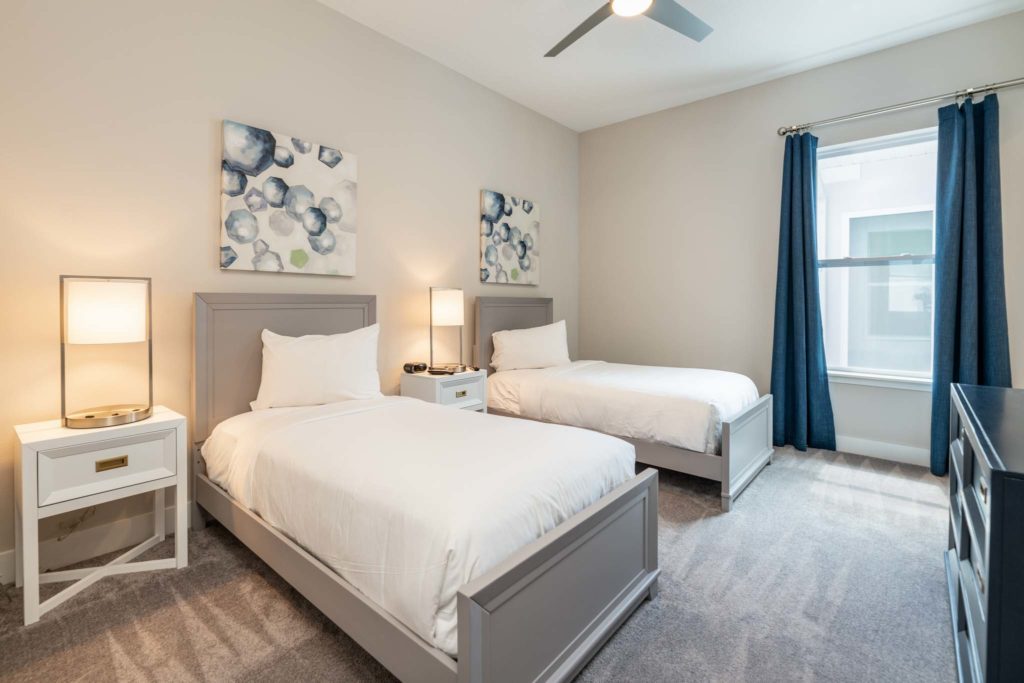 Twin beds with side tables under decorative wall art.
