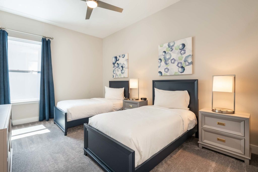 Twin beds under decorative wall art with side tables and modern lamps.