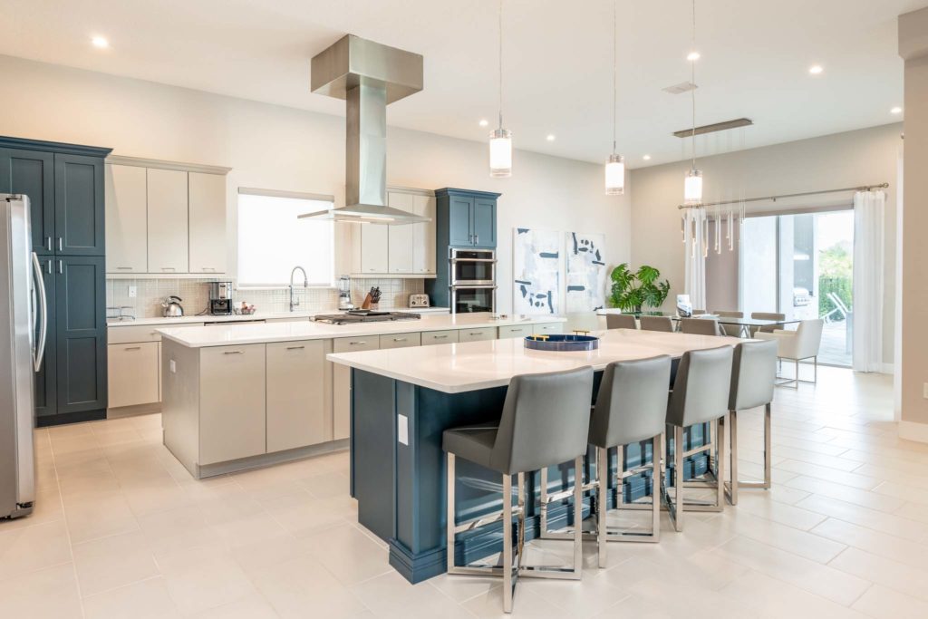 Spacious kitchen and dining room with two islands, barstool seats, and sliding door access to private backyard pool.