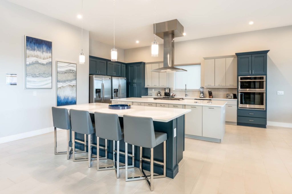 Deluxe kitchen with two islands, two refrigerators, and modern lighting.