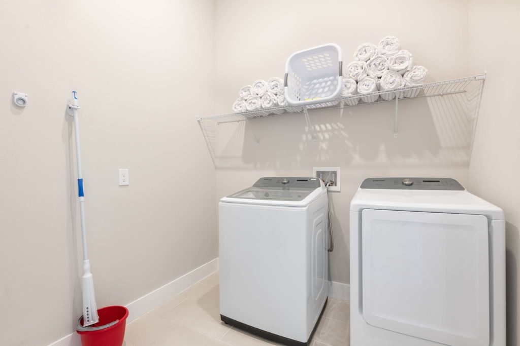 Laundry room with washer and dryer units and supplies.