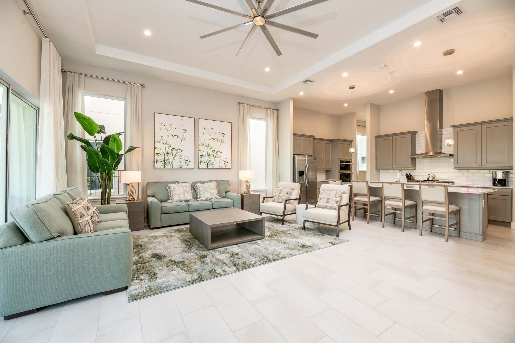 Spacious living room and kitchen with sofas, armchairs, and island barstool seating.