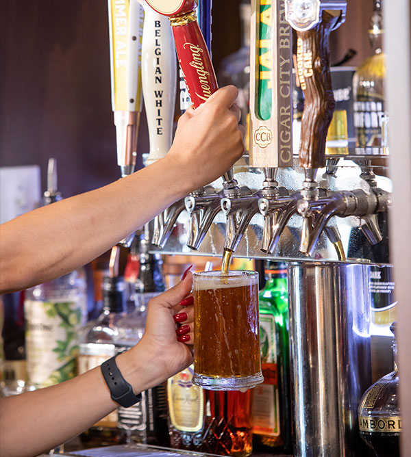Bartender pours a mug of beer.