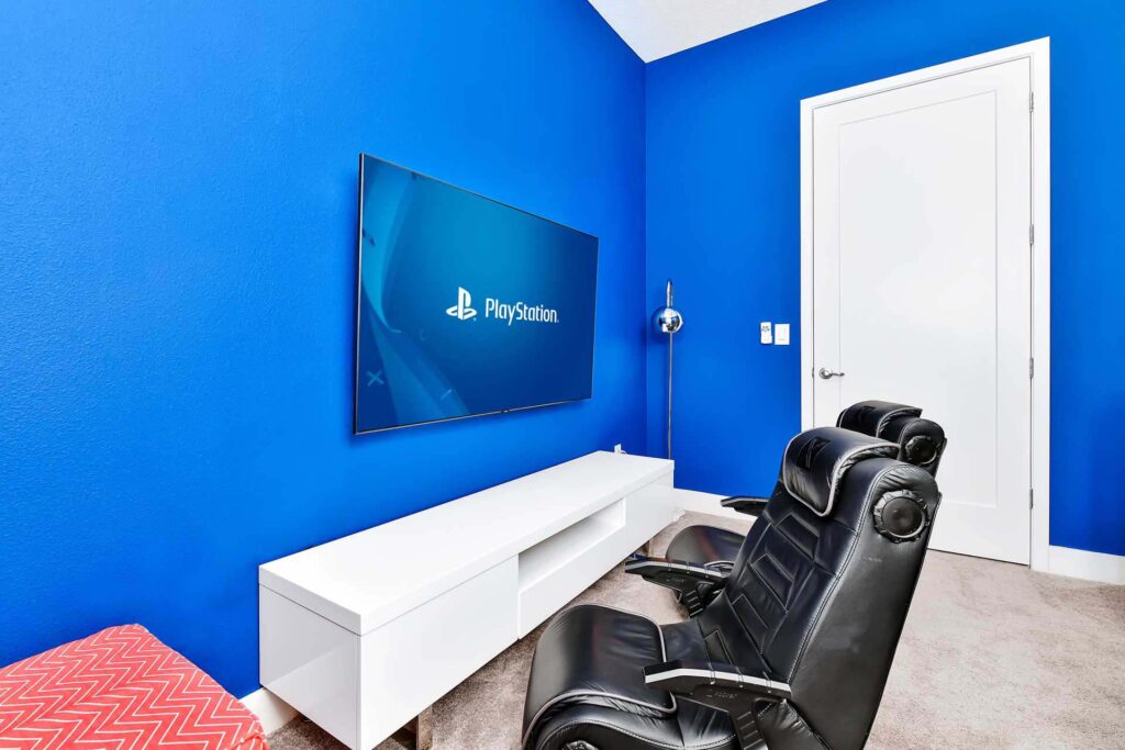 Video game area with gaming chairs and a large flat-screen tv at an enormous 8-bedroom Bear’s Den Resort Orlando residence
