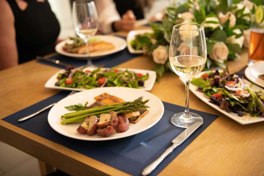 Dining Options 2 Plated salmon entree on a placemat next to a glass of wine | Bear's Den Chef Experience