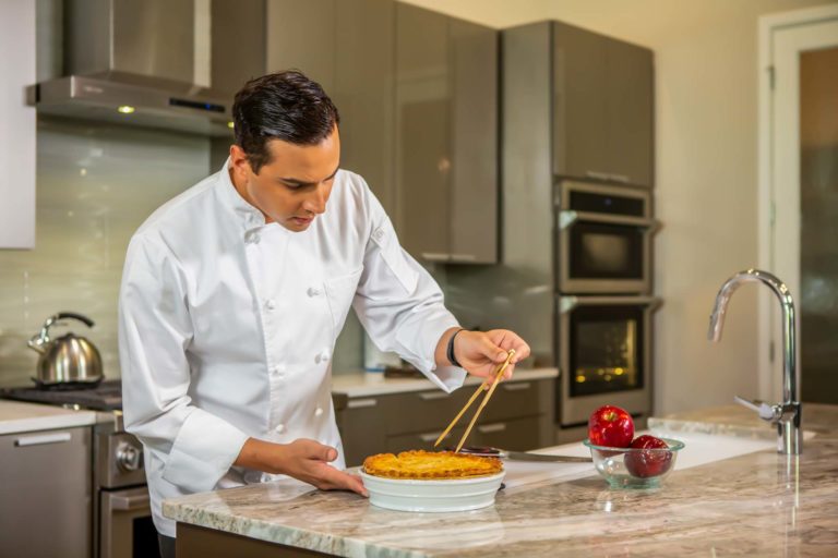 An expert chef prepares a meal during an in-home chef experience.