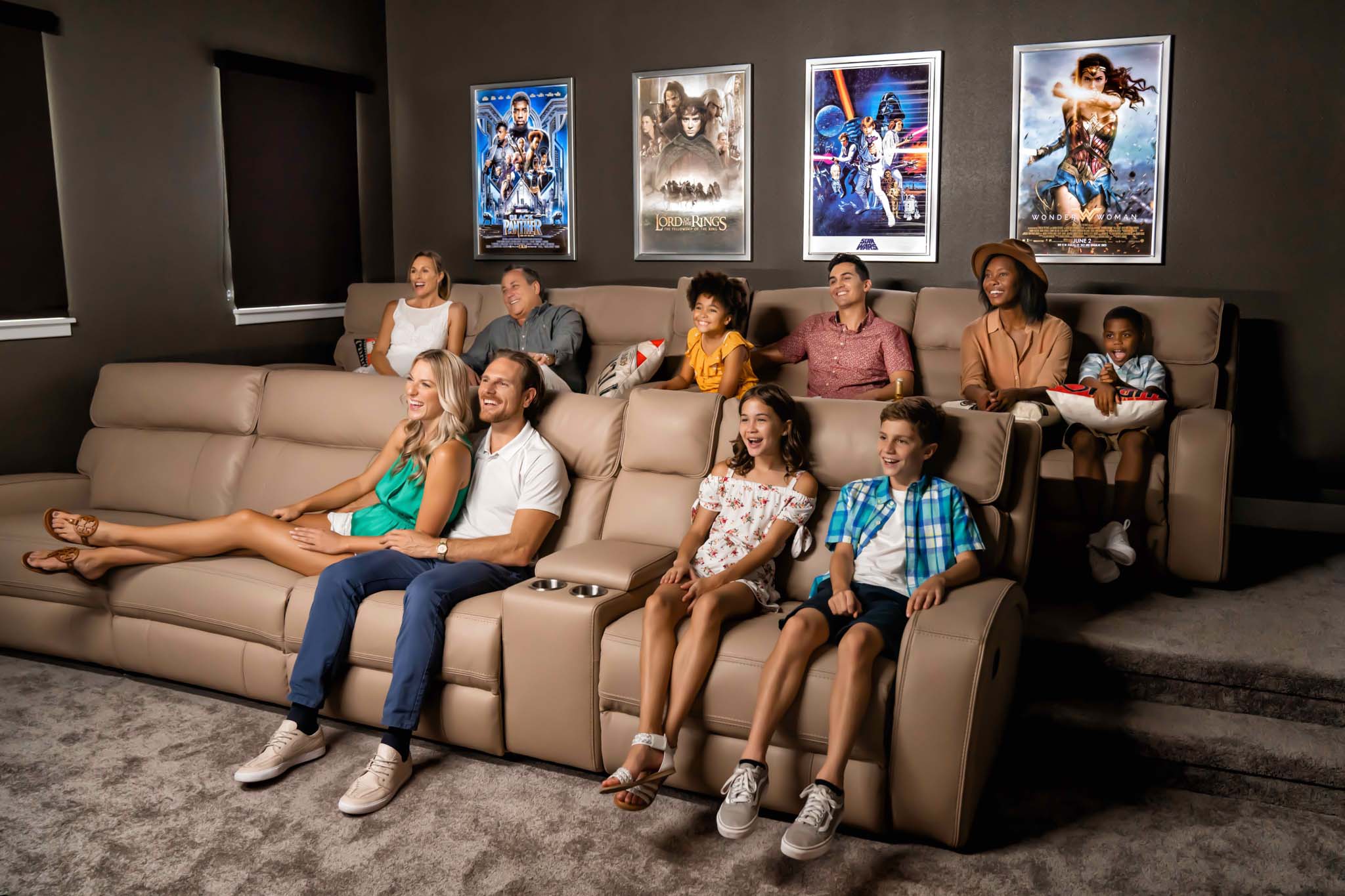 Large family of grandparents, parents, and kids happily watching a movie in a Bear’s Den Resort Orlando theater room.