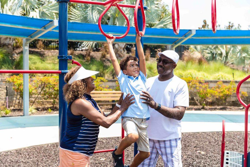 Grandparents helping their grandson on the jungle gym at the Bear's Den Resort