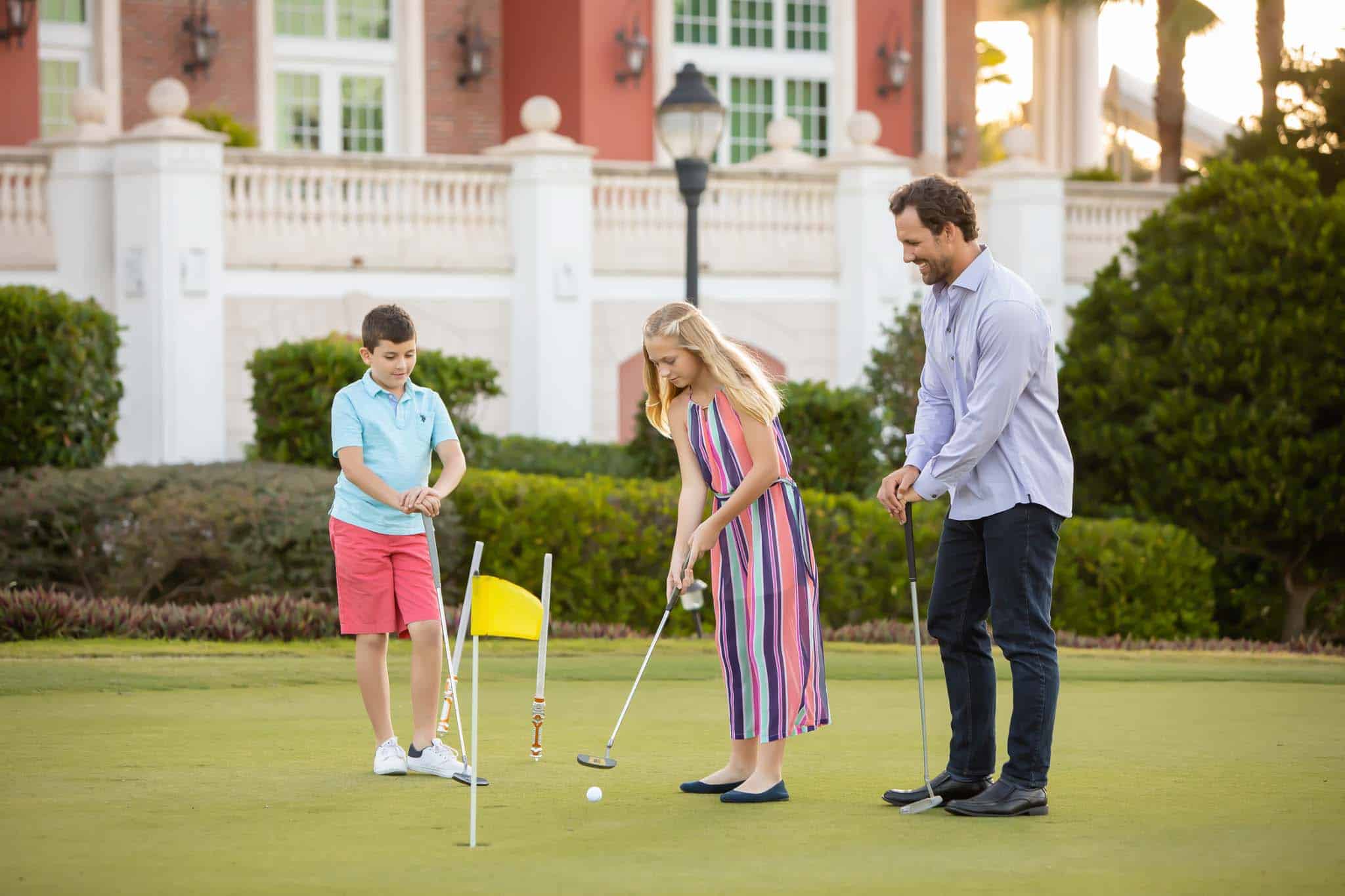 Dad watching his son and daughter put on the golf course.