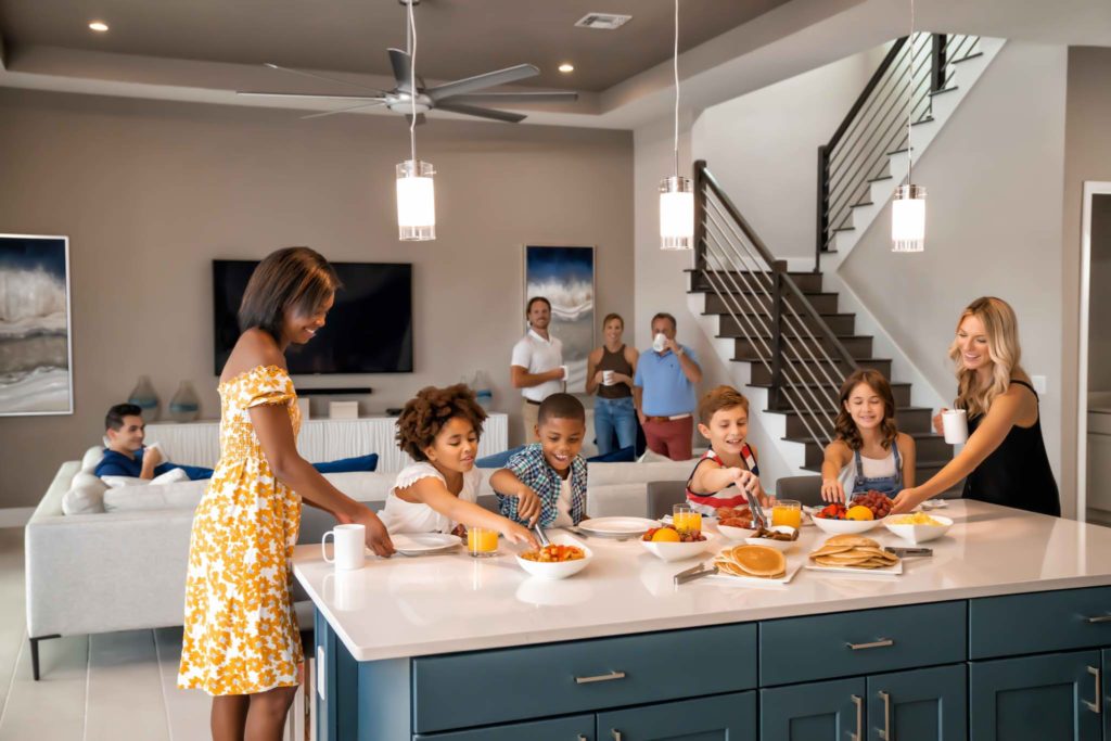 Kids sitting at a table set with an array of breakfast foods with their parents in a Bear’s Den resort residence.
