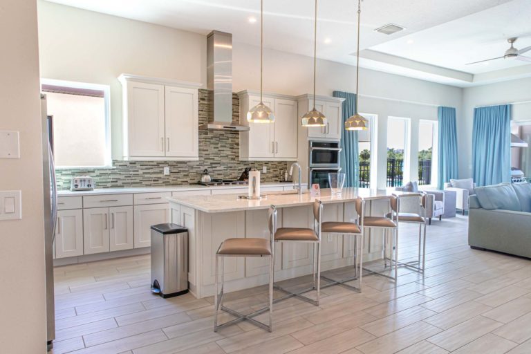 Furnished kitchen with island sink and countertop barstool seating inside a Bear’s Den Resort Orlando vacation home.