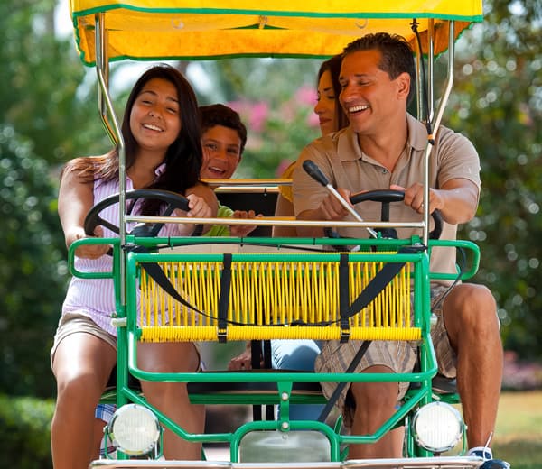 Family of four riding a covered Surrey bike together.