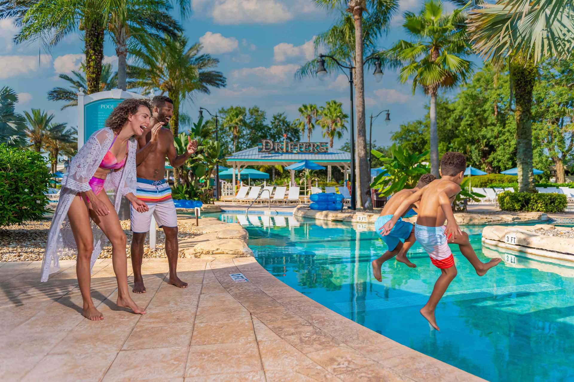 Parents laughing as their kids jump into the pool at the Water Park | Bear's Den Resort Orlando