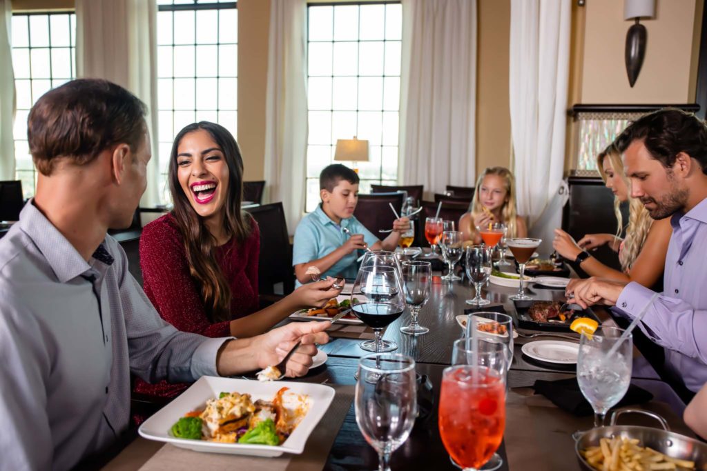 Family talking and laughing at a table at Traditions Restaurant.