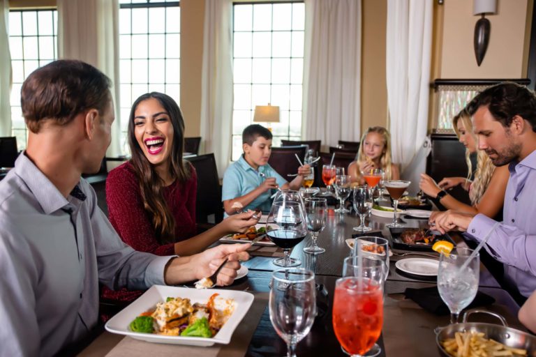 Family talking and laughing at a table at Traditions Restaurant.