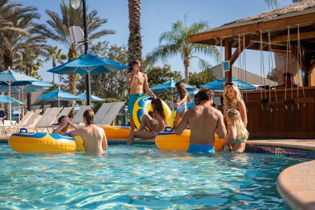 Families sitting on the edge of the pool with floating tubes at the Bear’s Den water park.