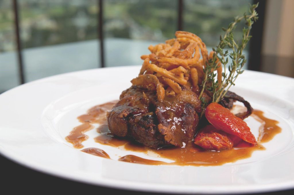 Premiere Resort Dining 2 Steak garnished with onion straws and sun-dried tomatoes.